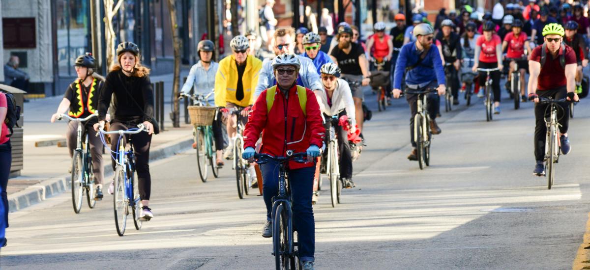 Lots of people bike down a roadway on a sunny day