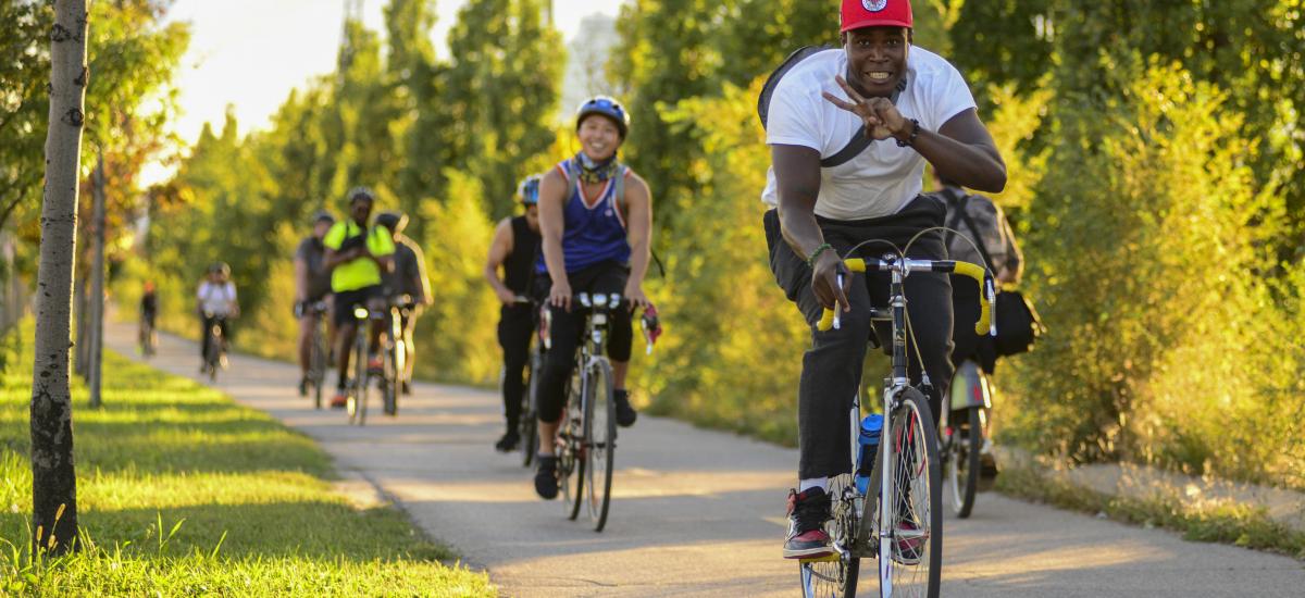 People ride bikes on a trail surrounded by greenery