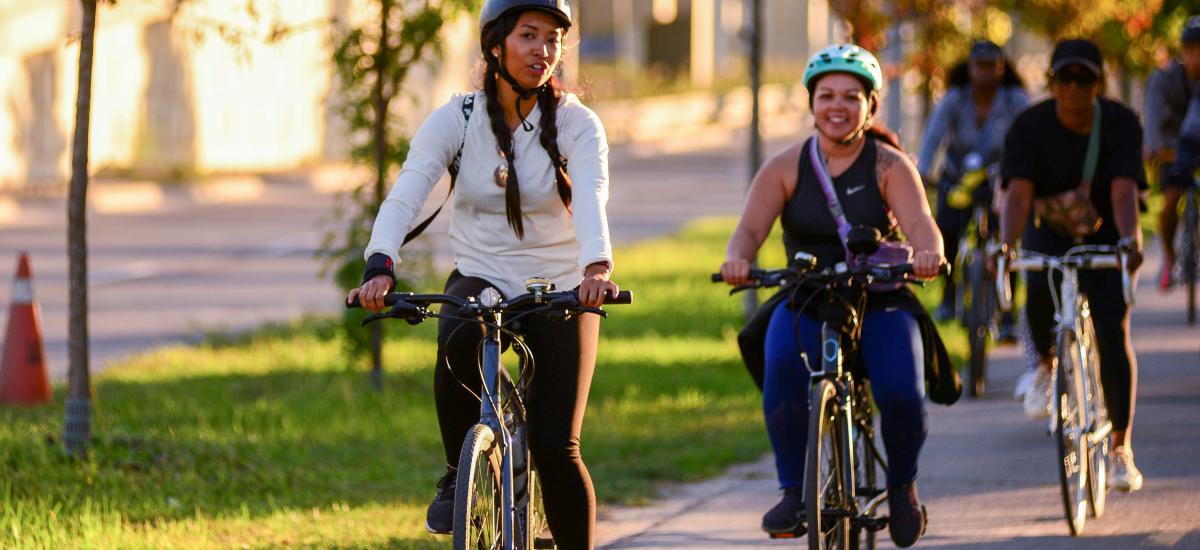 People ride bikes on a trail surrounded by greenery