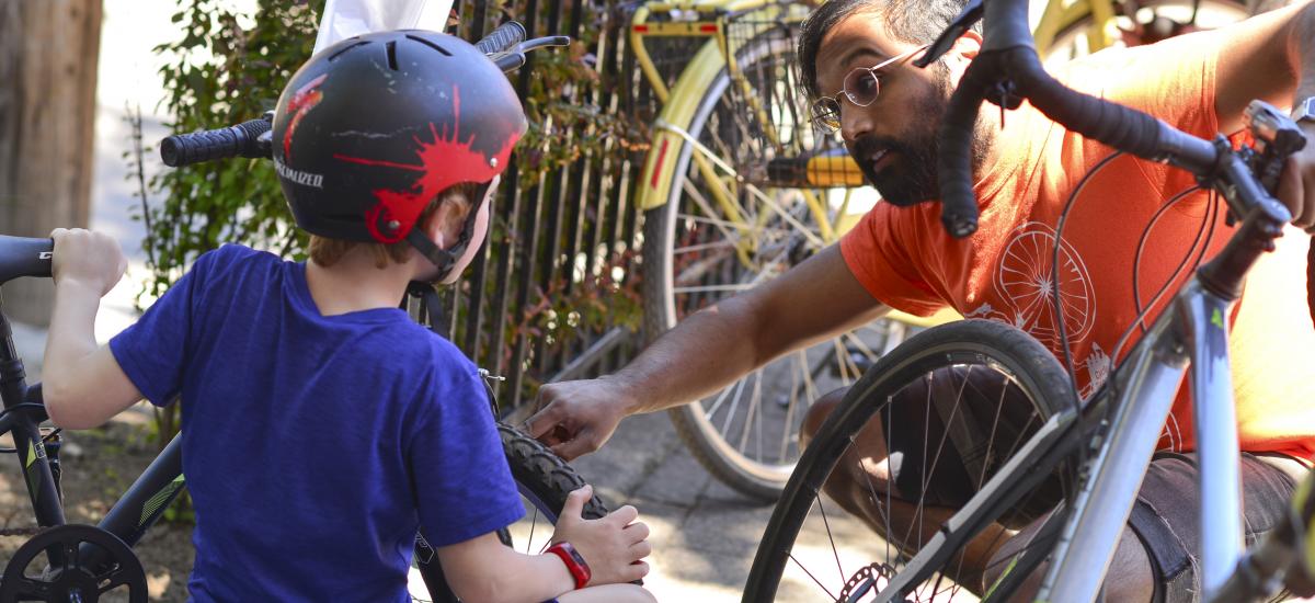 An adult teaches a child about a bike.