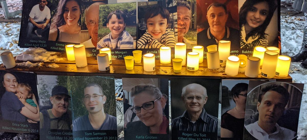 Candles sit beside posters of people with their birth and death dates