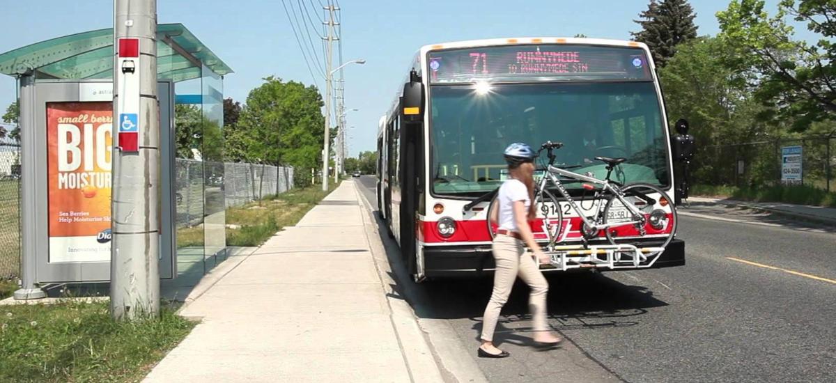 A bike on a bus with a woman locking it up