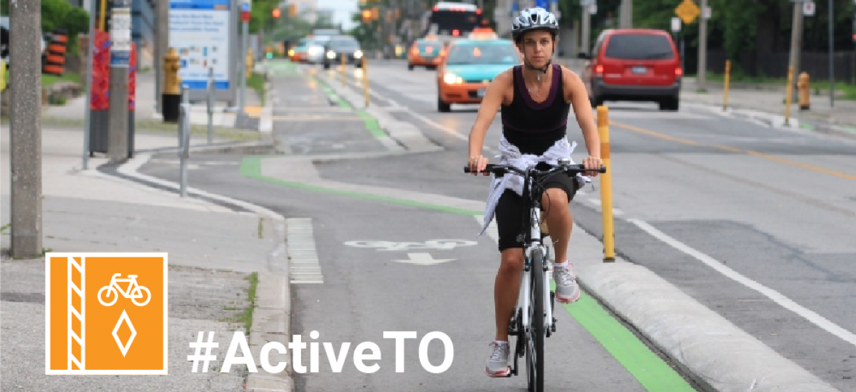 Hashtag Active T O. Person riding a bike in a protected bike lane. They're wearing a tank top and shorts.