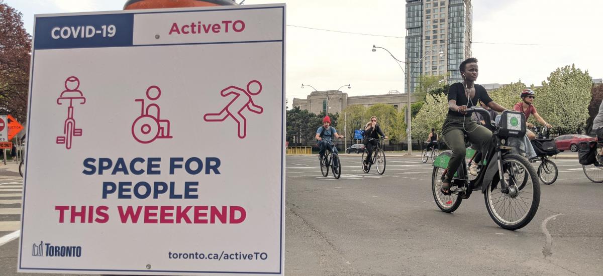 Sign reads "space for people" beside people riding bikes