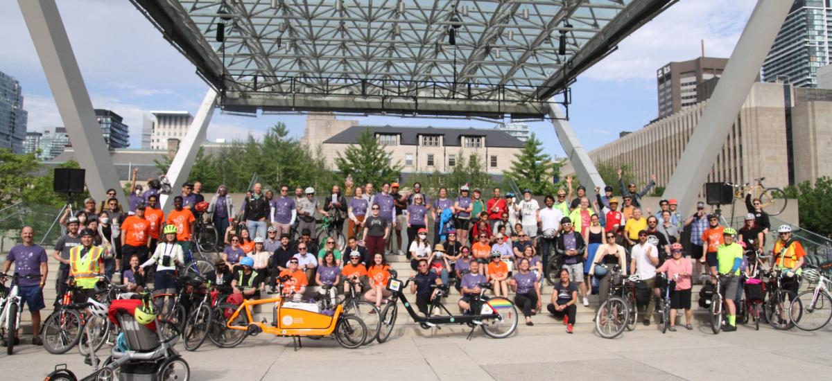 Dozens of people with bikes pose for a group photo in Nathan Phillips Square