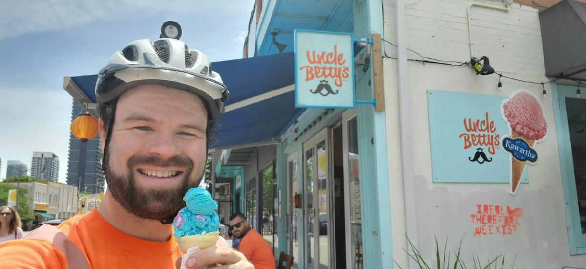 A man stands holding an ice cream cone in front of the store Uncle Betty's