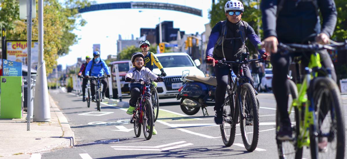 Many people ride bikes on Danforth Avenue including a child