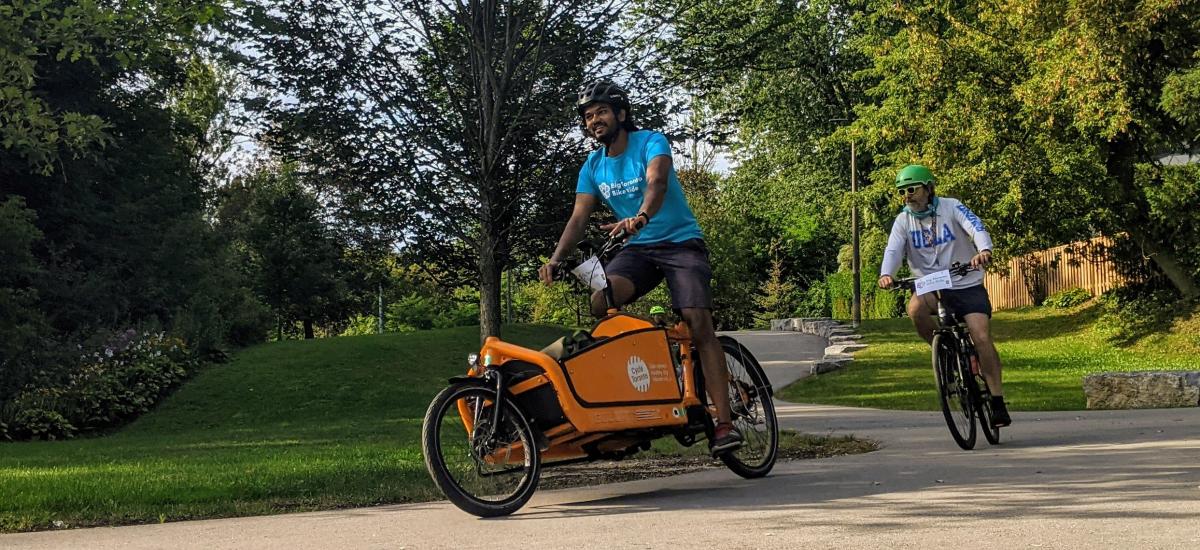 Kevin rides an orange Cycle Toronto cargo bike on a trail in Scarborough