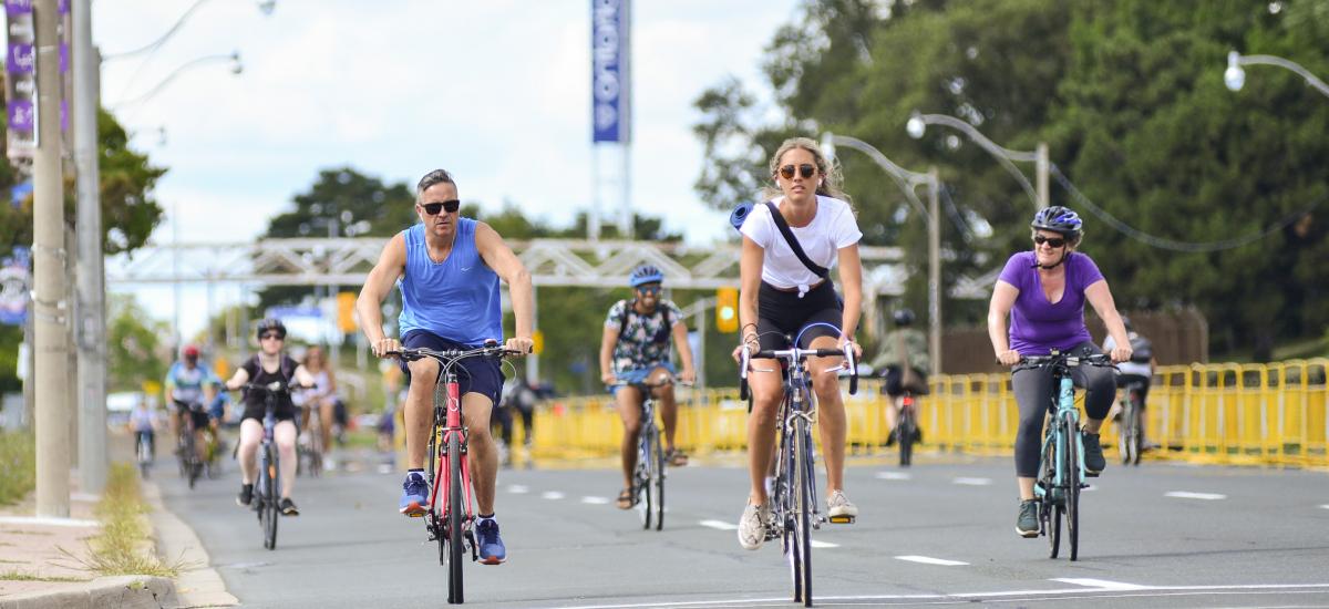 A photo of LakeShore Boulevard West shows that the eastbound lanes have been opened up to people to get around using active transportation. Many people are seen cycling on the road.