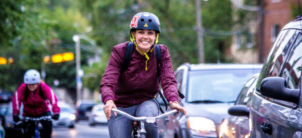 A woman smiles as she rides her bicycle in the foreground of the photo