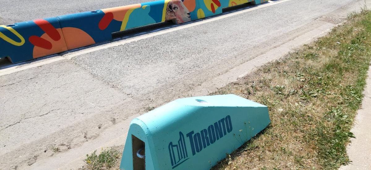 Colourfully painted low concrete walls. One has the Toronto City logo on it in blue.