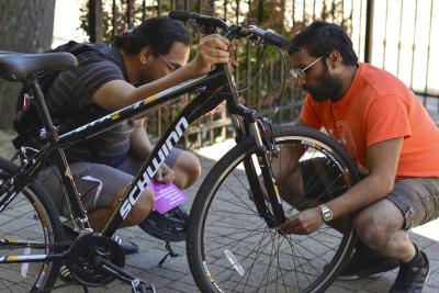 A man examines a bike wheel while his student looks on.