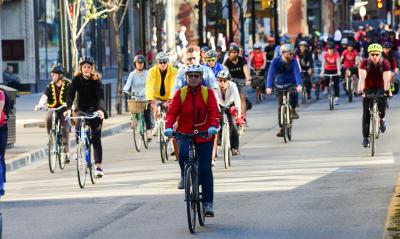 Lots of people bike down a roadway on a sunny day