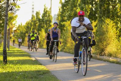 People ride bikes on a trail surrounded by greenery