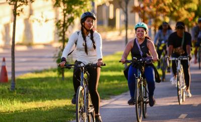 People ride bikes on a trail surrounded by greenery