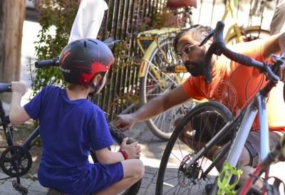 An adult teaches a child about a bike.