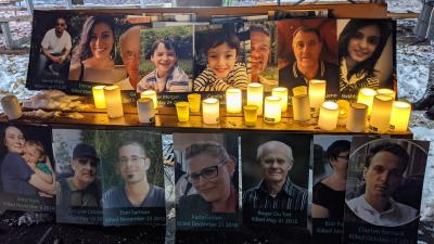 Candles sit beside posters of people with their birth and death dates