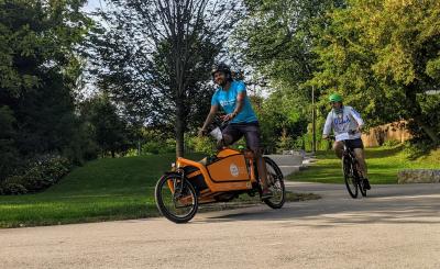 Kevin rides an orange Cycle Toronto cargo bike on a trail in Scarborough