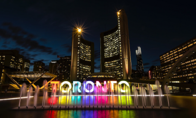 Multi-couloured Toronto sign at night with a water fountain in front of it