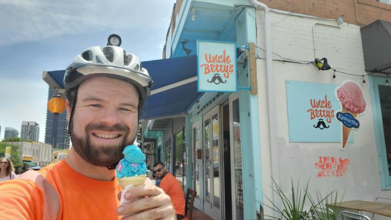 A man stands holding an ice cream cone in front of the store Uncle Betty's