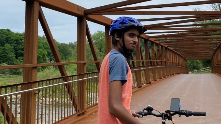 Hafeez Alavi poses with his bike on a bridge in a valley