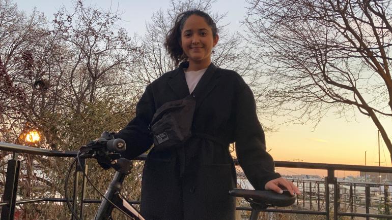 Sonam stands beside her bike as the sun sets over Lake Ontario