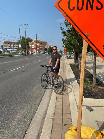 A person stand by their bike on a wide road