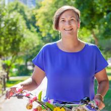 Alison stands beside a bike with flowers on it