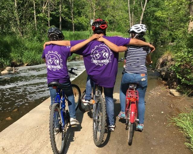 Three chilren embrac while seated on bikes