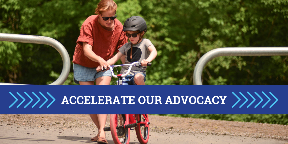 An adult assists a child on a bike. Text reads "Accelerate our advocacy"