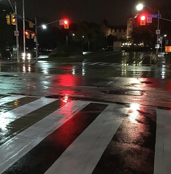 Wet roads reflect street lights at night.