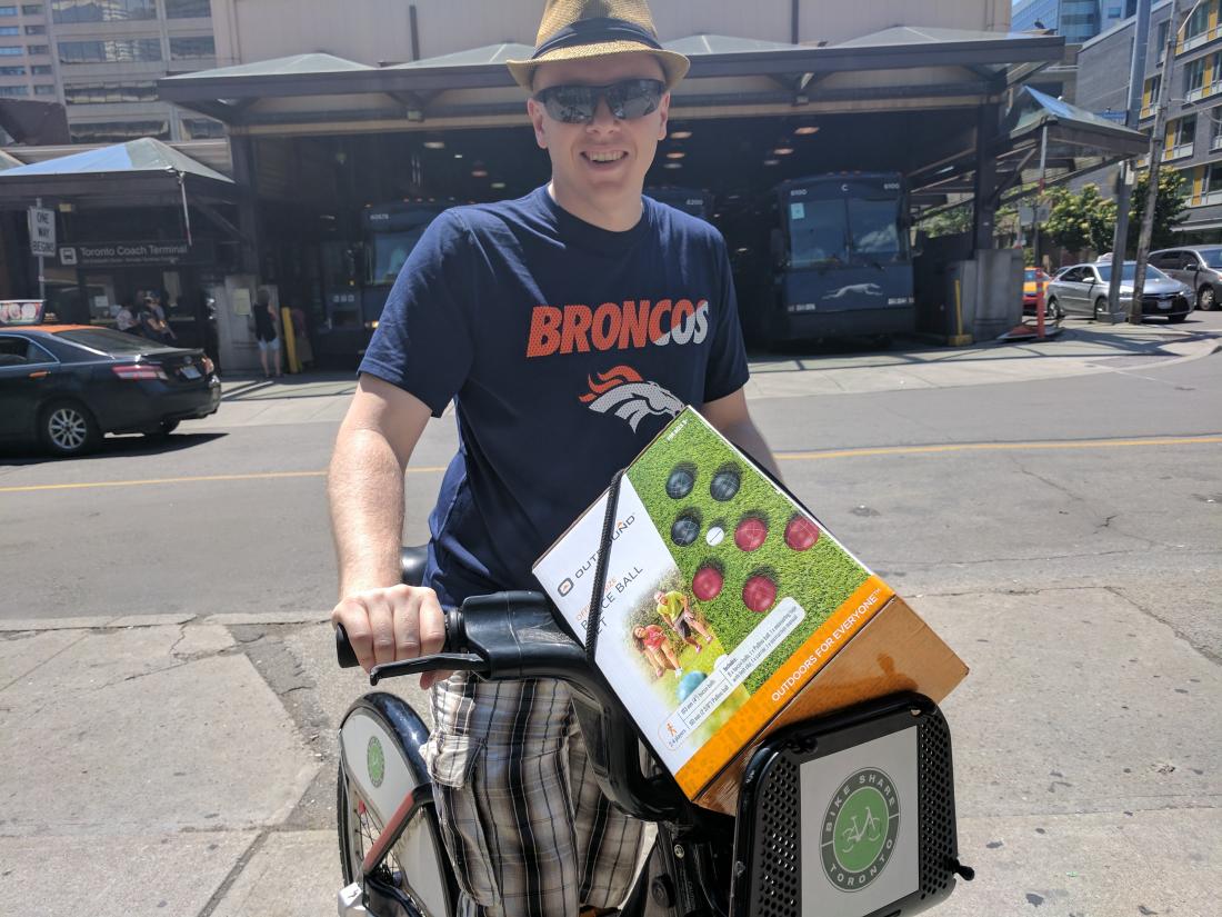 person standing with a Bike Share Toronto bike with bocce balls in the basket