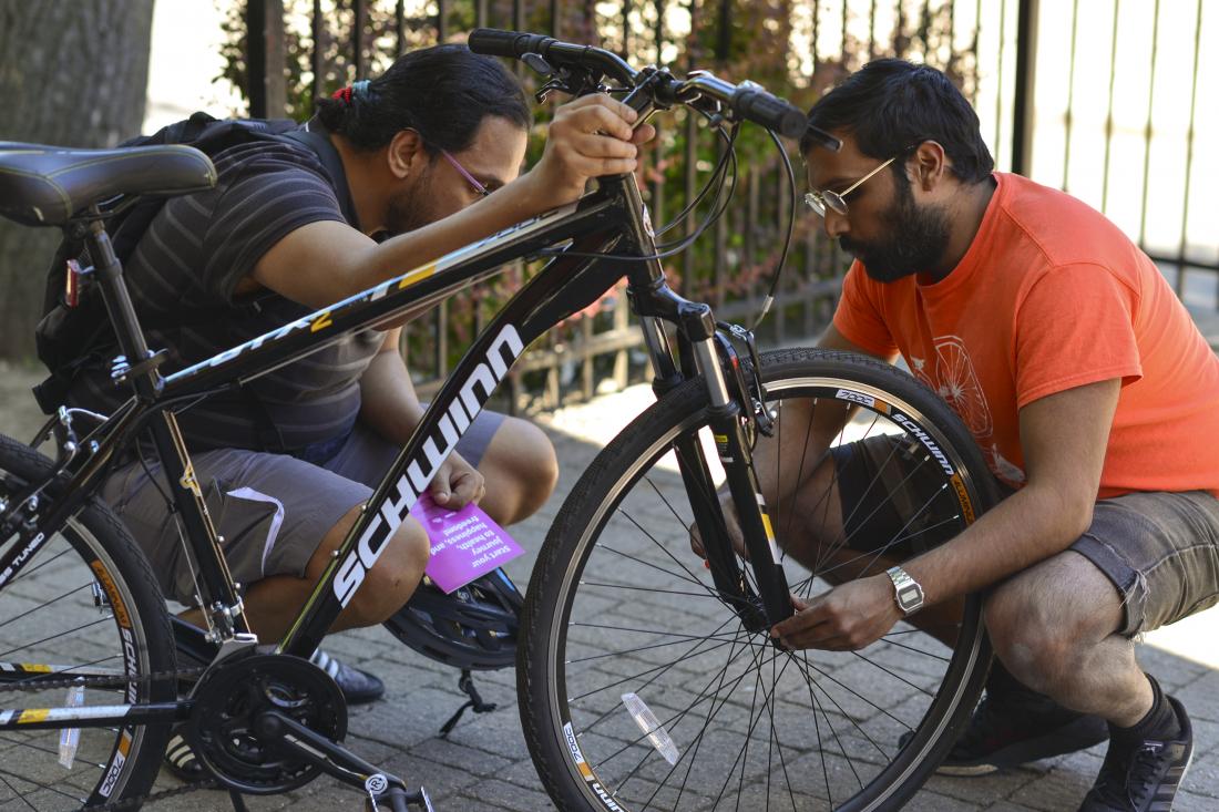 Cycling educator instructs adult student on how to check their quick release