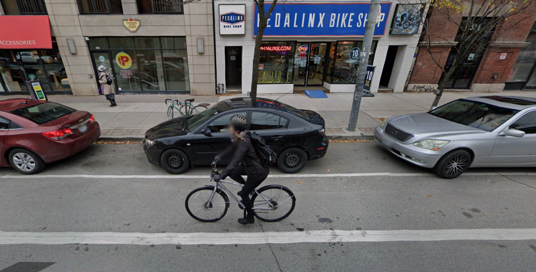 Person rides a bike in a painted bike lane beside cars