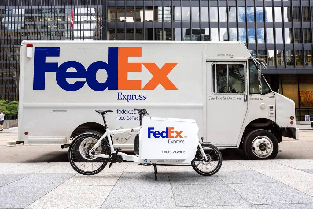 A FedEx van sits idle behind a FedEx Cargo Bike