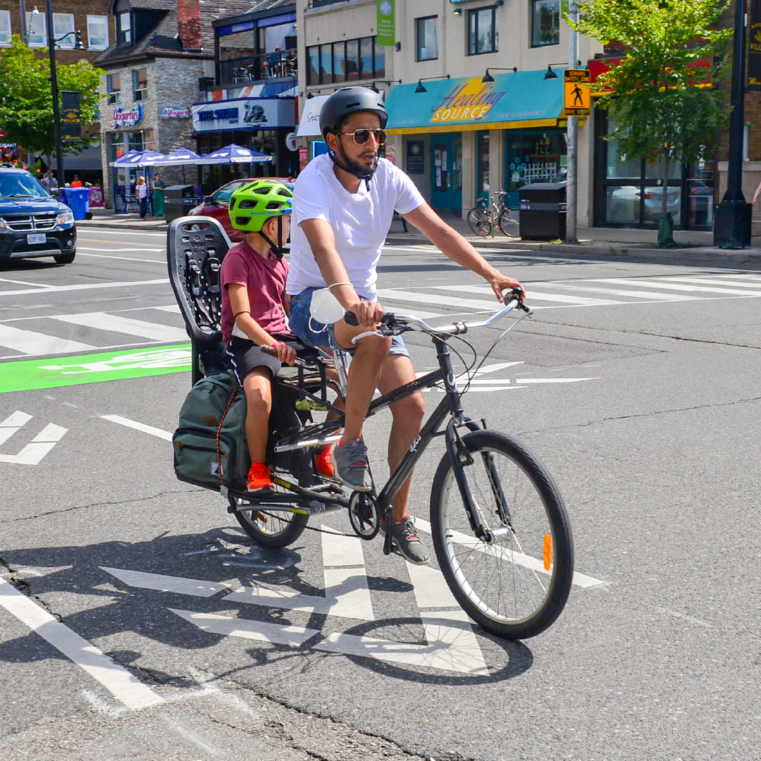 A person rides a bike with a child in a child seat.