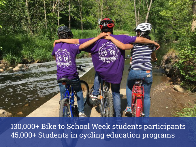 Three students hug while sitting on bikes