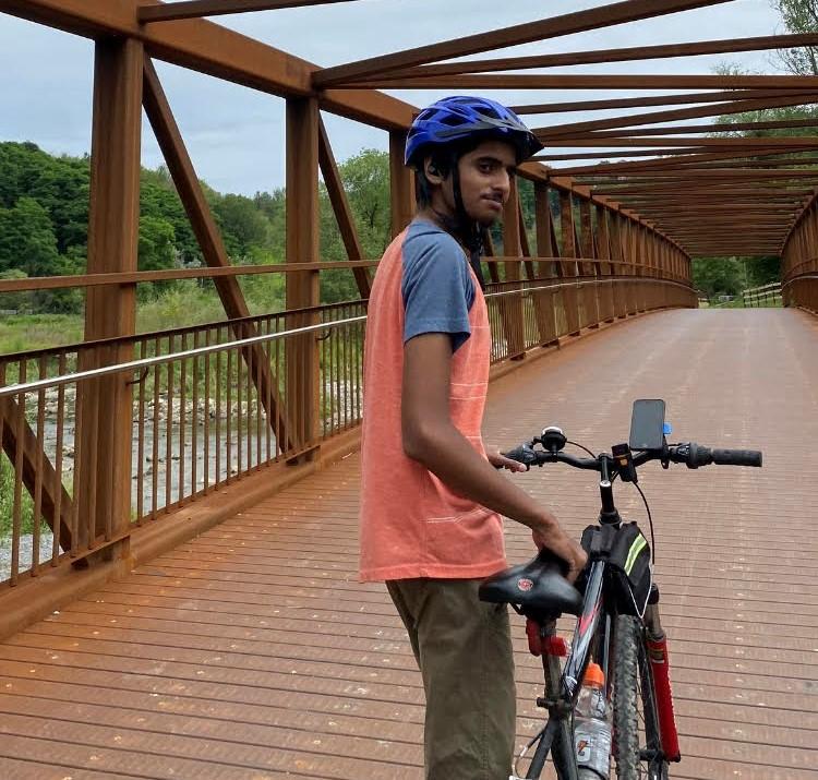 Man poses with his bike on a bridge