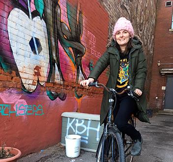 Theresa on her bike with mural in the background