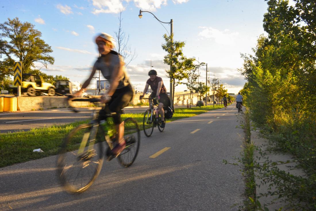 At sunset people ride on a paved path that is separate from traffic.