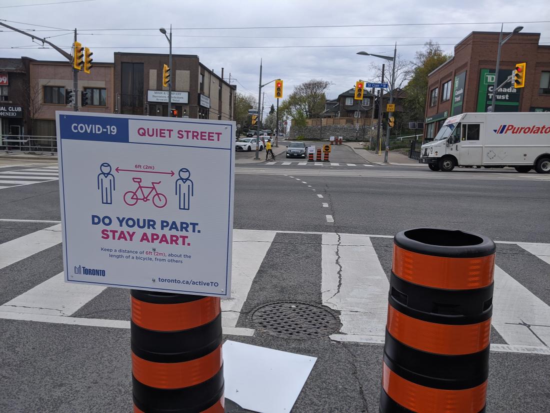 Sign and orange barrels in middle of street indicate that it is a Quiet Street for sharing