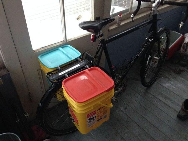 Two large kitty litter tubs attached to a bike rack