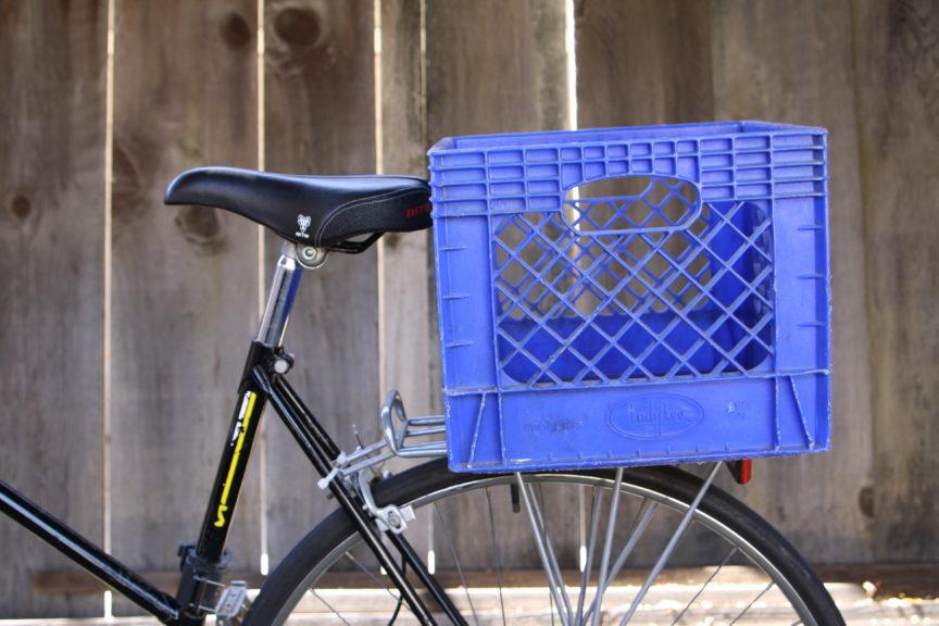 Blue milk crate attached to bike rack